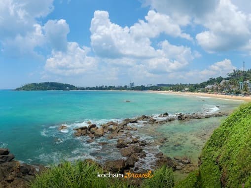 Panoramiczny widok tropikalnej zatoki z plażą i zielenią.
