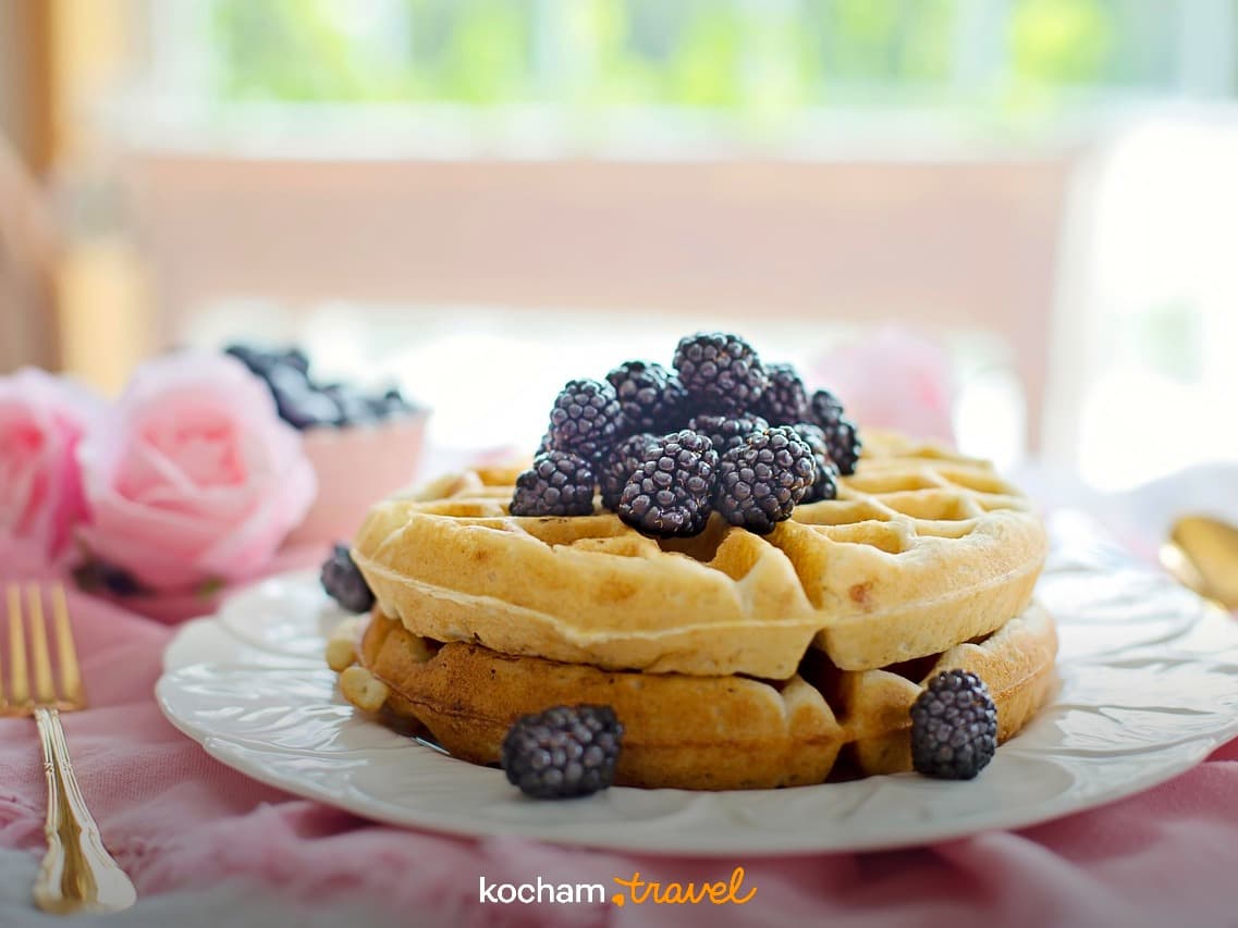 Świeże wafle z jeżynami, różowe róże, złote sztućce, jasne śniadanie.