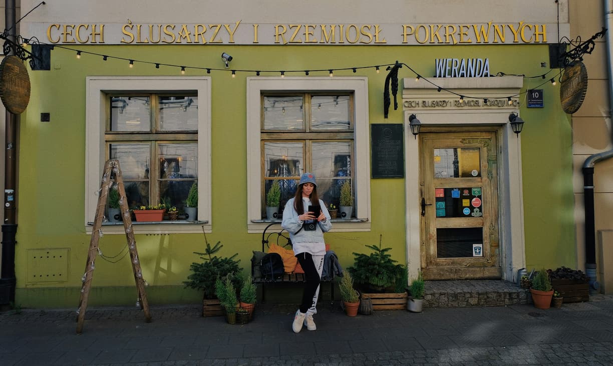 Młoda kobieta przed zabytkowym budynkiem Cechu Ślusarzy i Werandy.