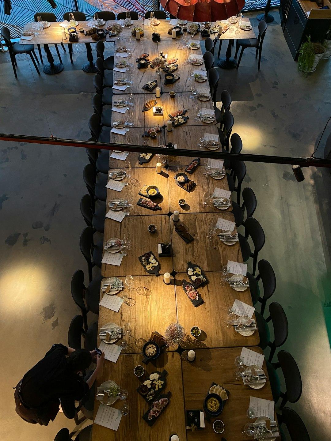 Długi drewniany stół w restauracji z deskami serów i przekąskami.