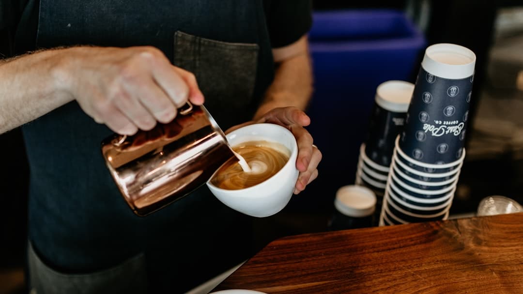 Barista przygotowuje kawę z mlekiem latte art.