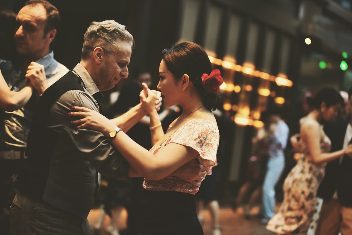 Elegancka para tańczy namiętne tango; kobieta ma czerwony kwiat.