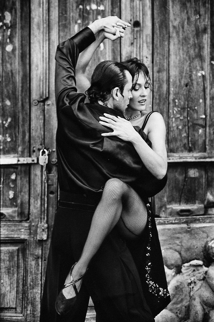 Namiętny taniec tango eleganckiej pary przed drewnianymi drzwiami.