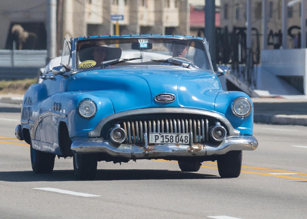 Niebieski zabytkowy Buick kabriolet z pasażerami na ulicy Kuby.