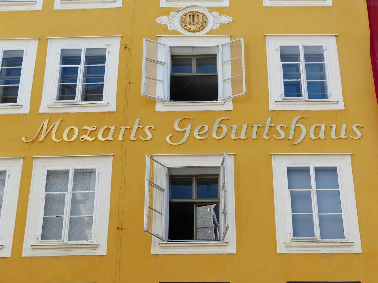 Żółta fasada Domu Urodzenia Mozarta z otwartymi oknami.