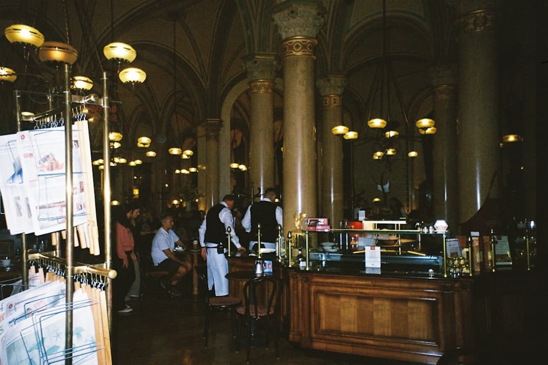 Eleganckie wnętrze kawiarni z kolumnami, kelnerami i ciepłym oświetleniem.