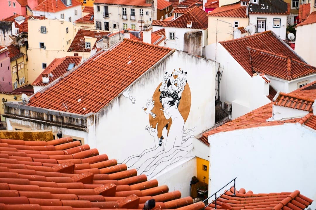 Malownicze dachy Lizbony, kolorowe budynki i artystyczny mural.