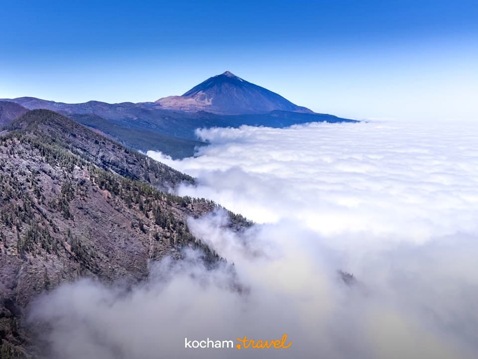 Szczyt wulkanu Teide nad morzem chmur, słoneczny widok panoramiczny.