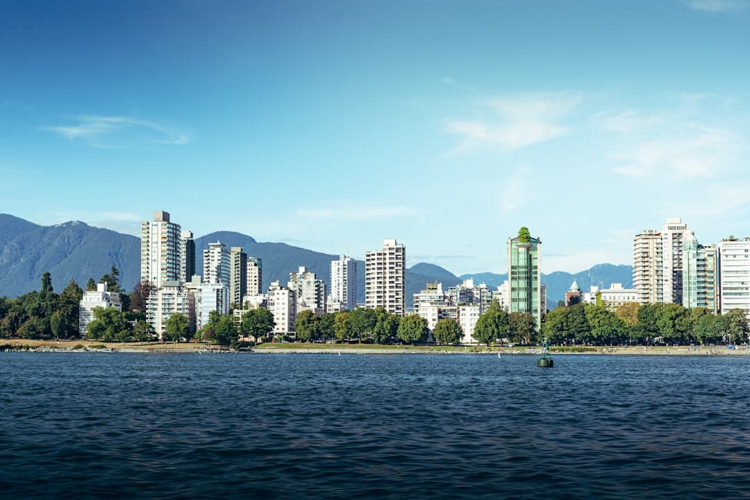 Miasto Vancouver, wieżowce, góry, woda, linia brzegowa, błękitne niebo.