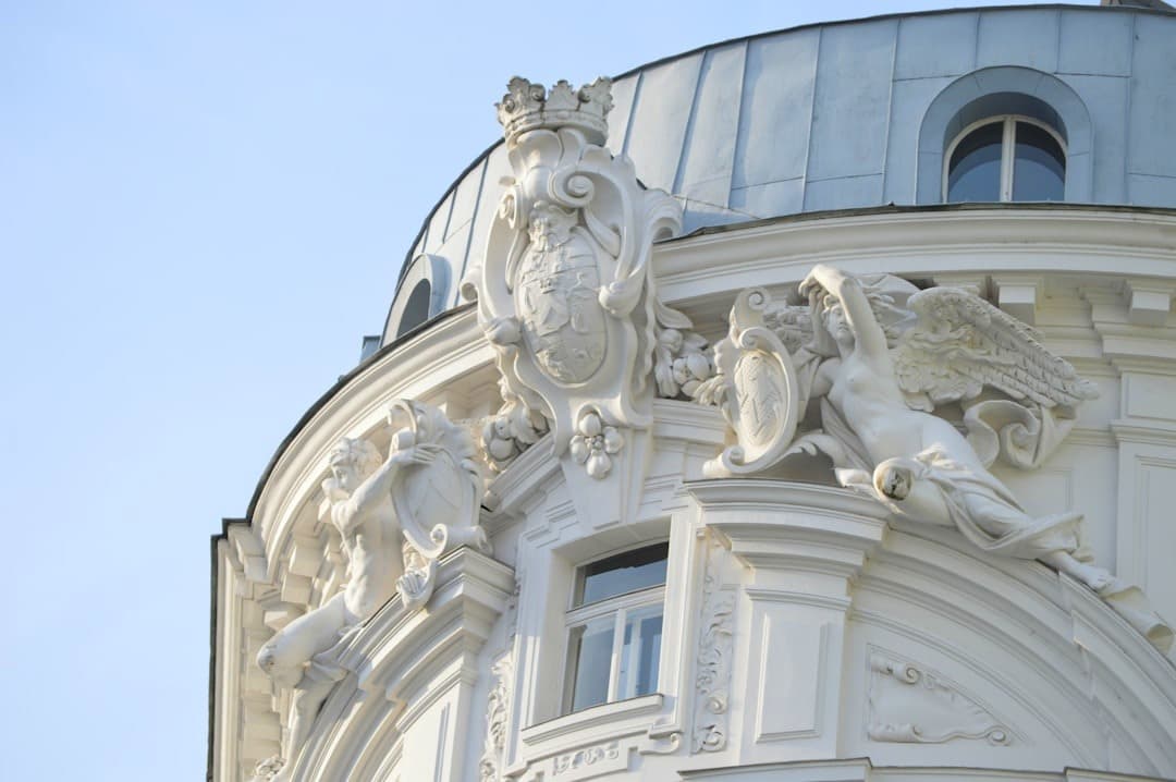 Białe detale architektoniczne, rzeźby i kopuła na tle błękitnego nieba.