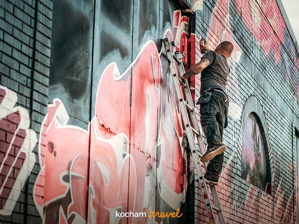 Artysta graffiti malujący kolorowy mural na ścianie budynku.