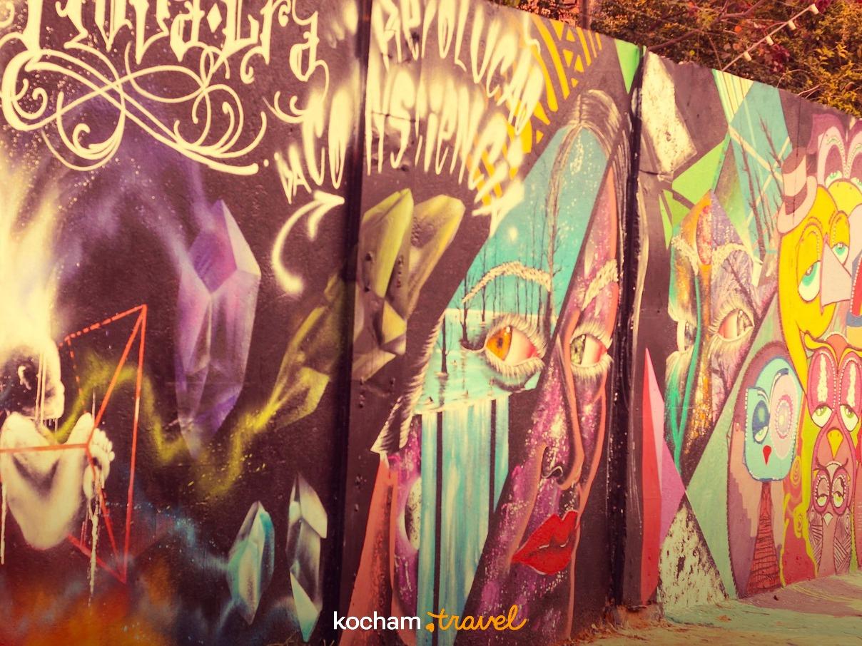 Kolorowe graffiti mural na ścianie, miejska sztuka, abstrakcyjne twarze i kryształy.