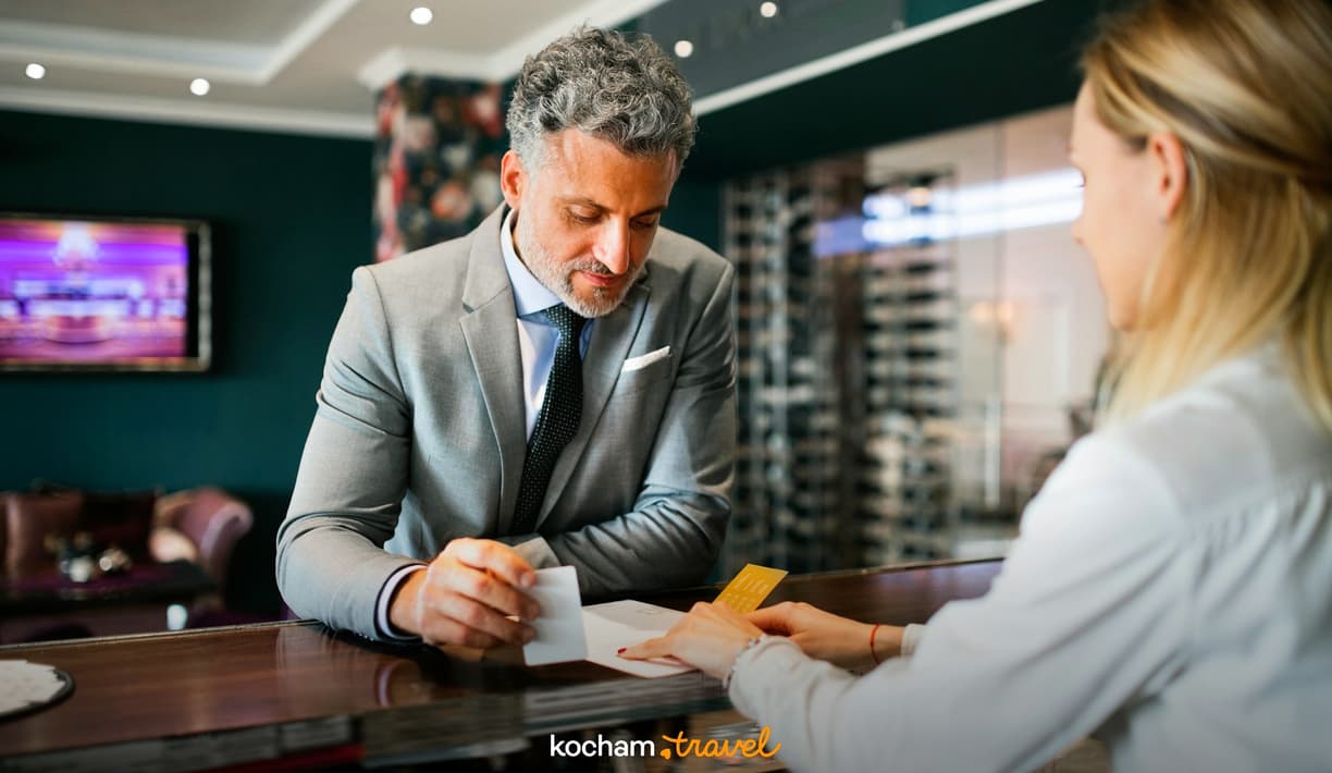 Biznesmen melduje się w hotelu, odbierając klucz-kartę od recepcjonistki.