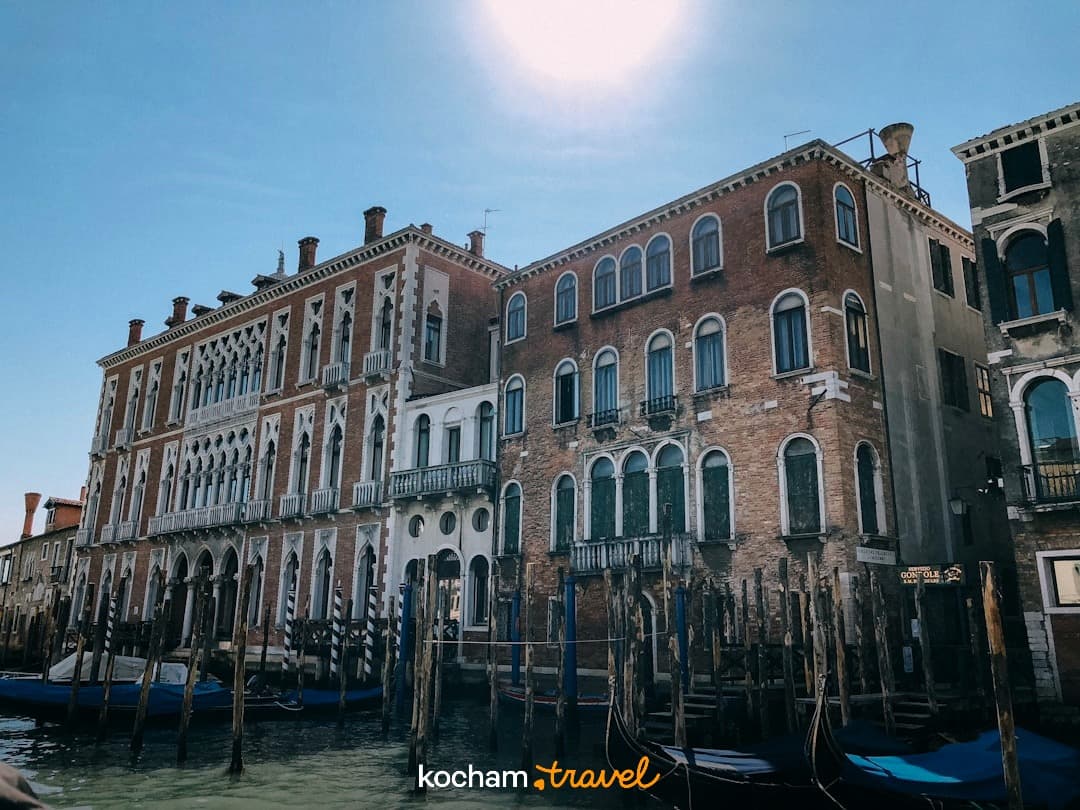 Wenecja kanał z zabytkową architekturą i zacumowanymi gondolami w słońcu.