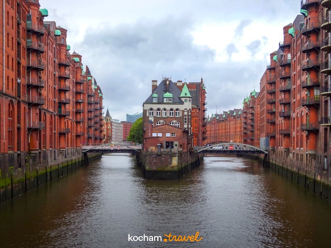 Historyczne magazyny z czerwonej cegły w Speicherstadt, Hamburg, nad kanałem, pochmurne niebo.