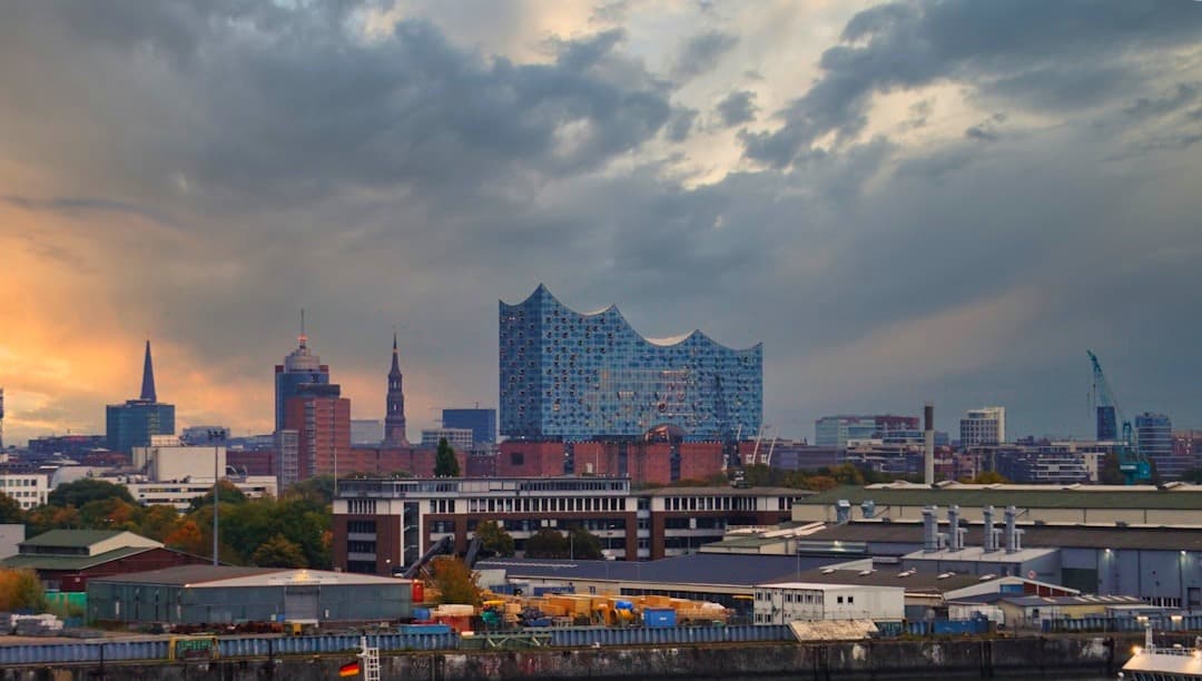 Panorama Hamburga z Elbphilharmonie, zachmurzone niebo i ciepłe światło.