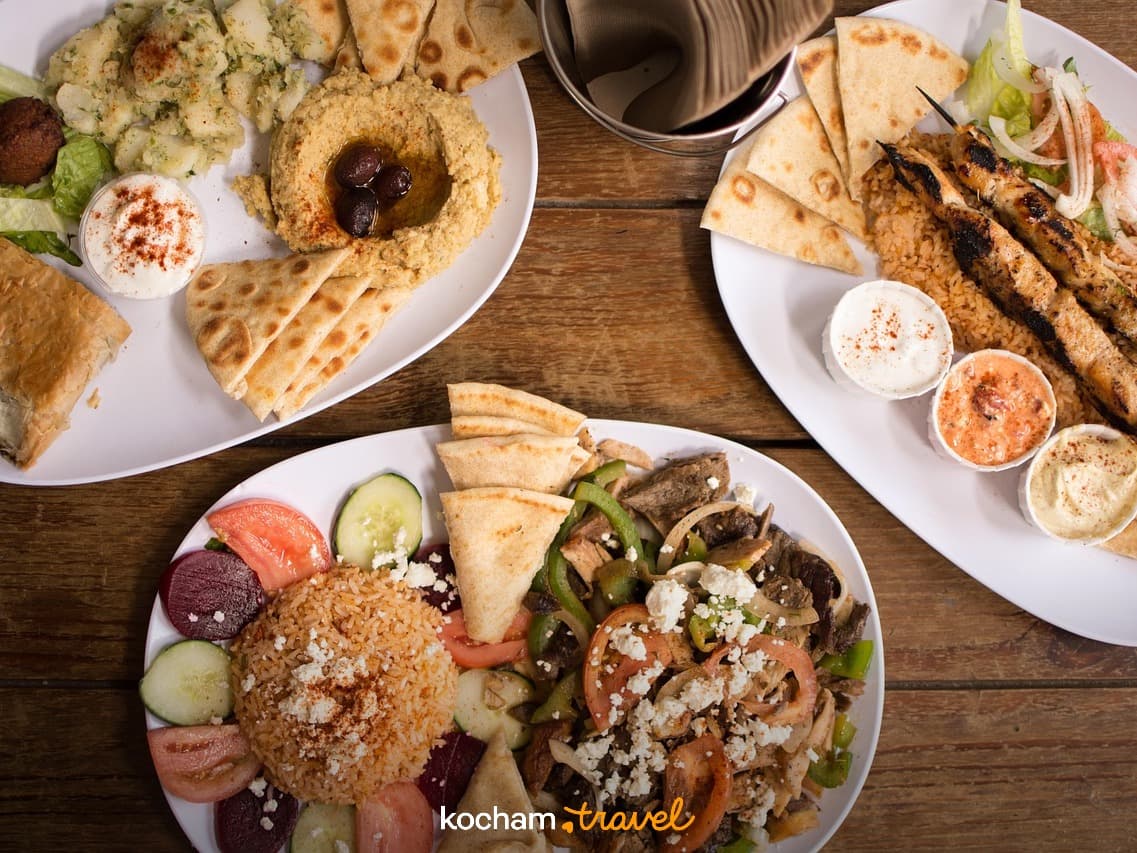 Różnorodne, żywe dania śródziemnomorskie, kebaby, hummus, chleb pita.