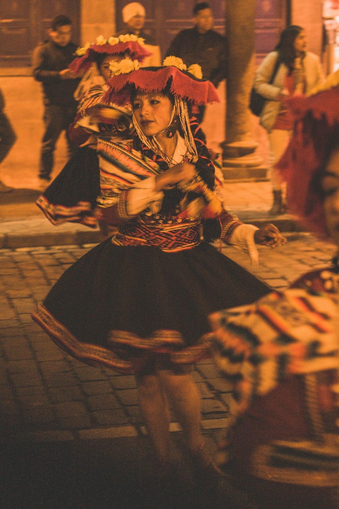 Kobieta w tradycyjnym stroju andyjskim tańcząca na ulicy podczas festiwalu.