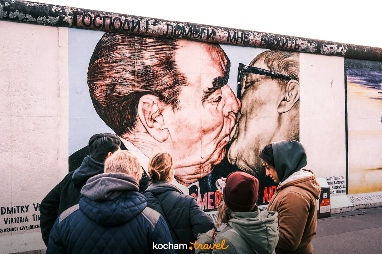 Turyści oglądają słynny pocałunek braterski na East Side Gallery w Berlinie.