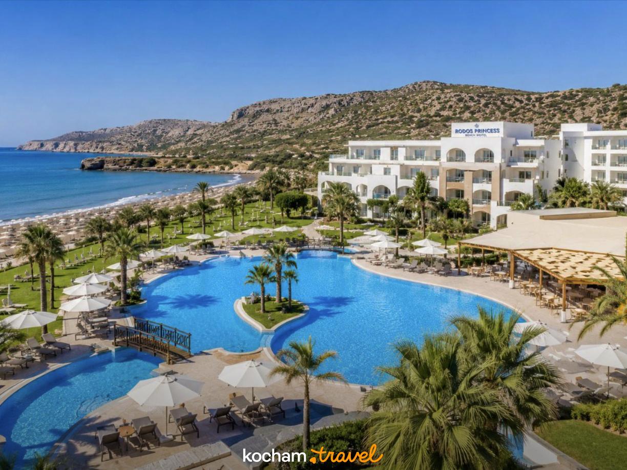 Rodos Princess Beach Hotel, rozległy basen, plaża i palmy.