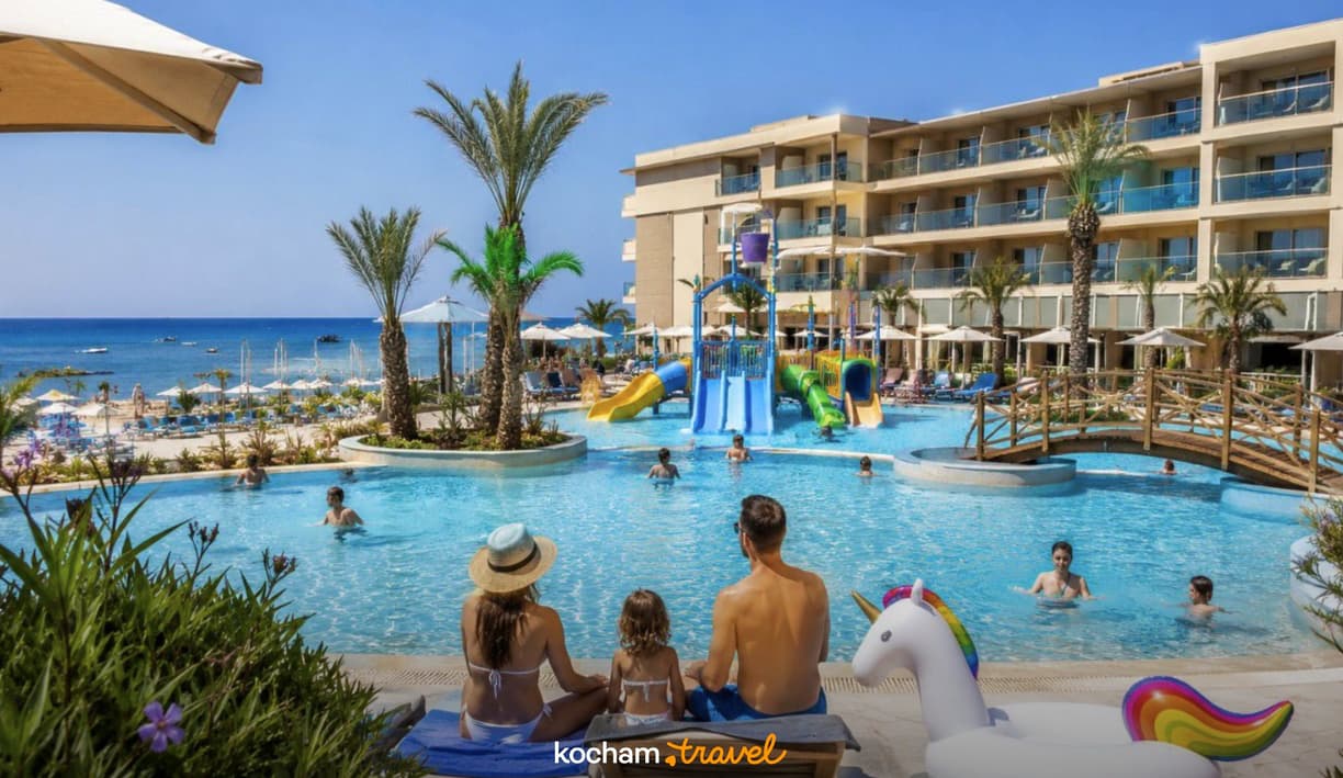 Słoneczne wakacje rodziny przy basenie hotelu z aquaparkiem i plażą.