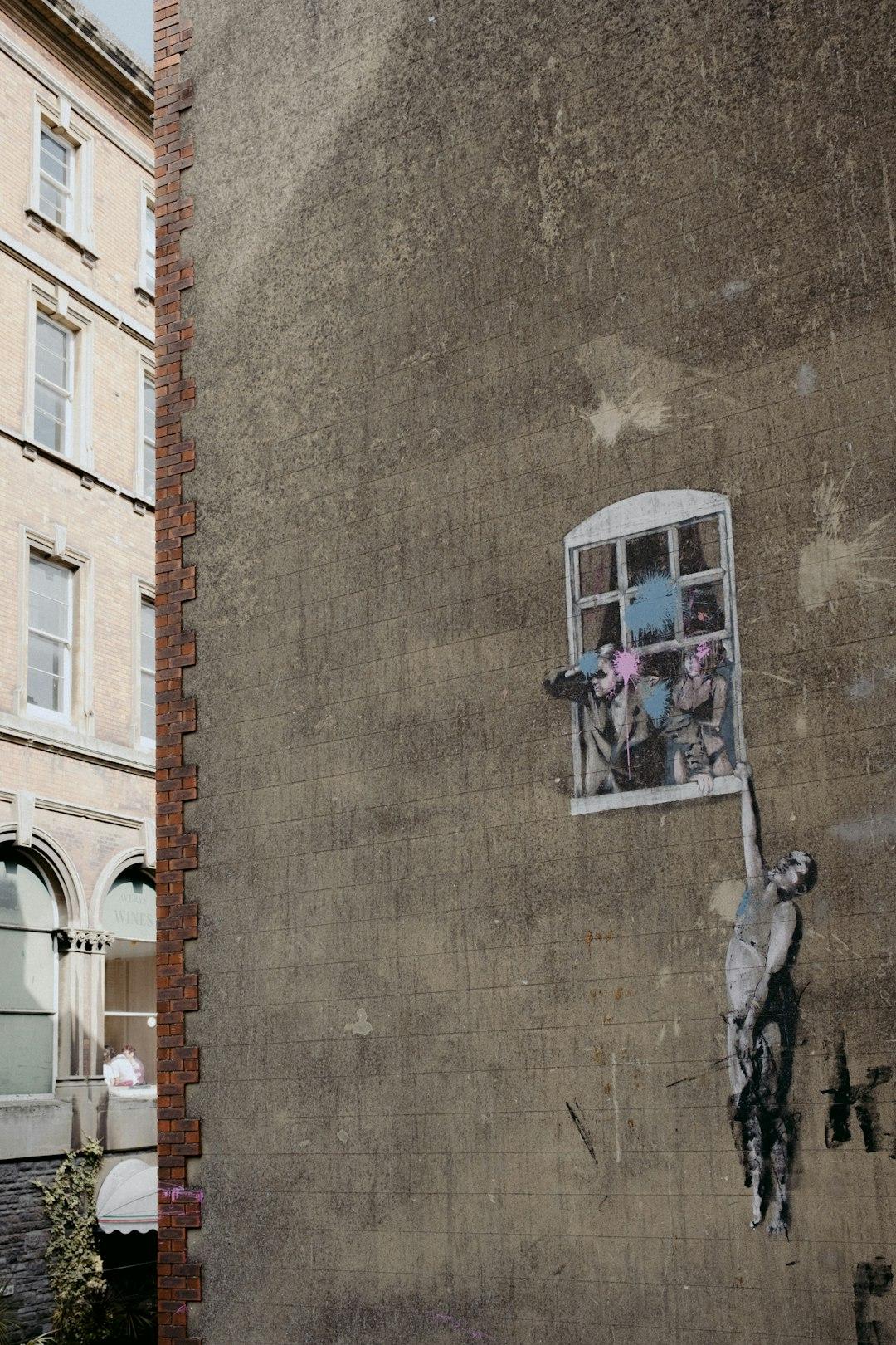 Uliczne graffiti: wiszący mężczyzna, para w oknie, szara ściana.
