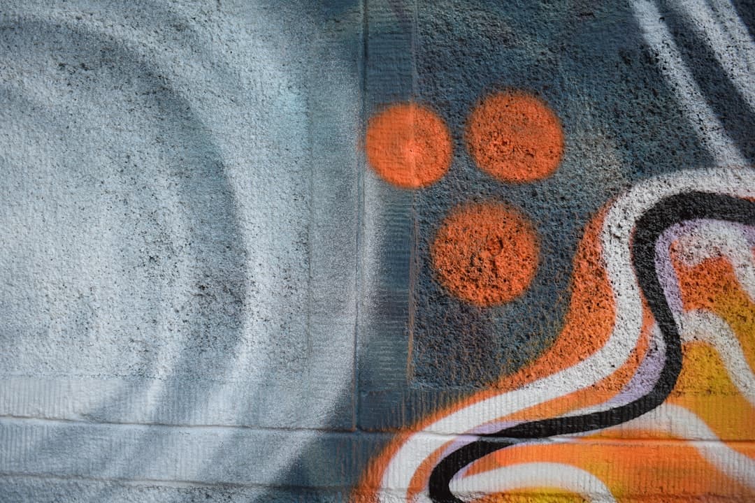 Graffiti na ścianie, abstrakcyjne pomarańczowe koła i kolorowe linie.