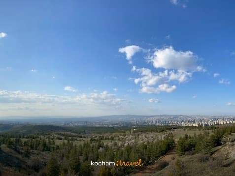 Panoramiczny widok miasta z zalesionego wzgórza, błękitne niebo, jasne słońce.