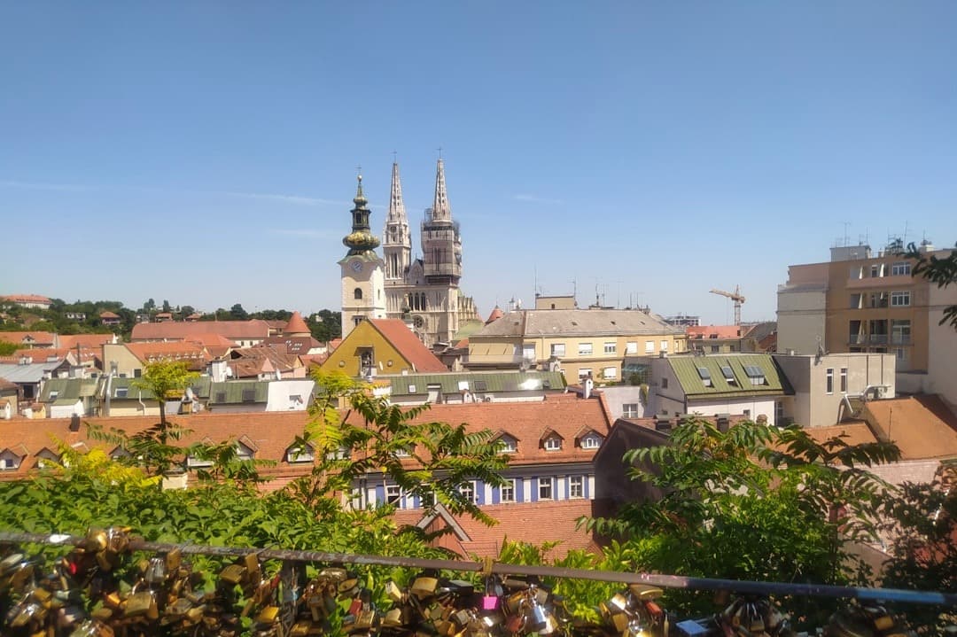 Panorama Zagrzebia z katedrą, czerwonymi dachami, kłódkami miłości w słońcu.