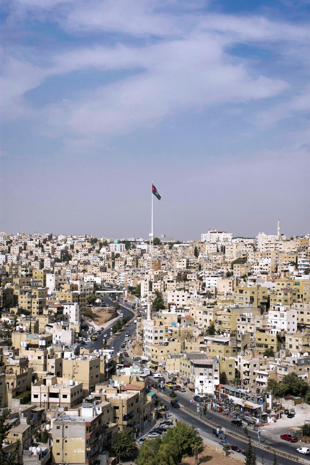 Panorama Amman z flagą na maszcie w centrum.