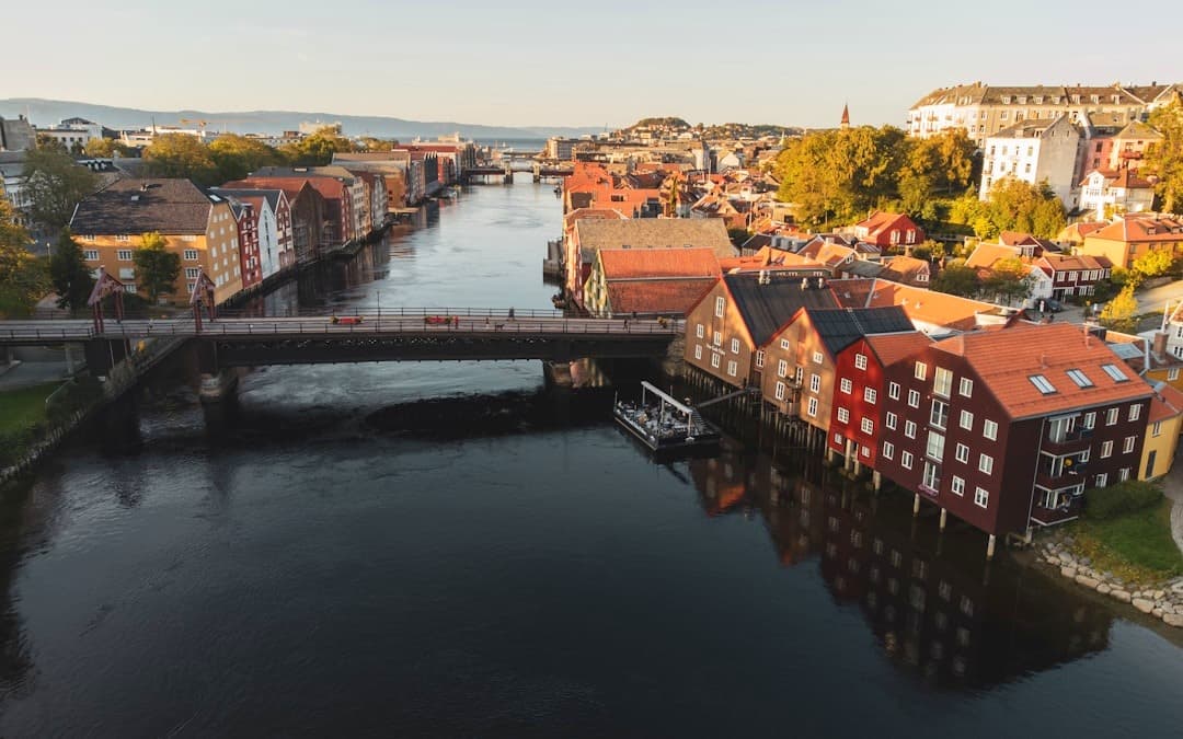 Kolorowe domy nad rzeką Nidelva w Trondheim, Norwegia, o zachodzie słońca.