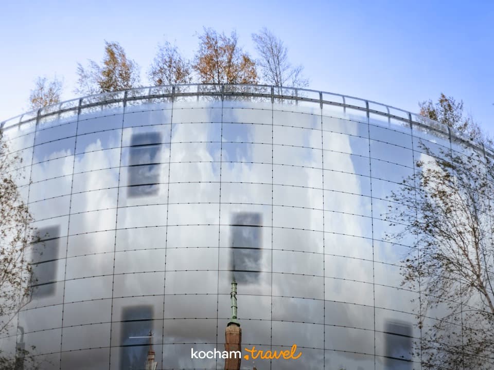 Nowoczesna architektura, zakrzywiony budynek, szklana fasada, odbicia nieba i chmur.