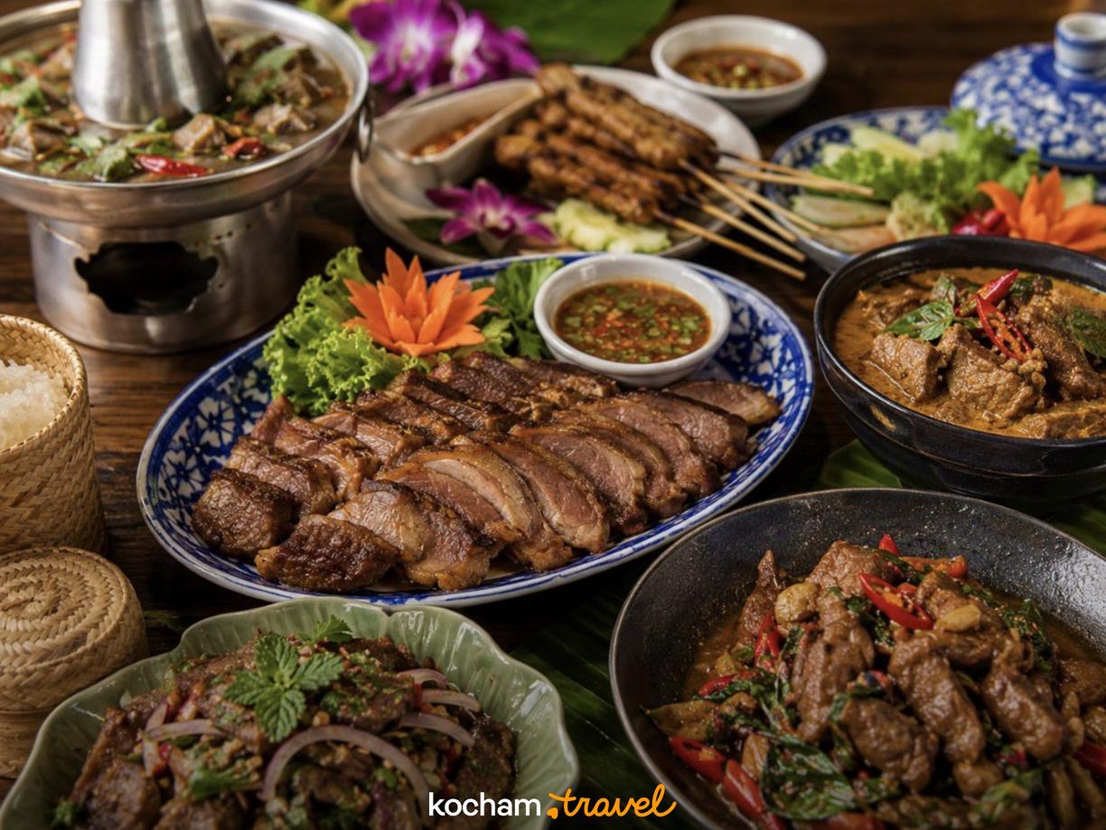 Różnorodne tradycyjne dania kuchni tajskiej, w tym curry, satay i grillowane mięso.