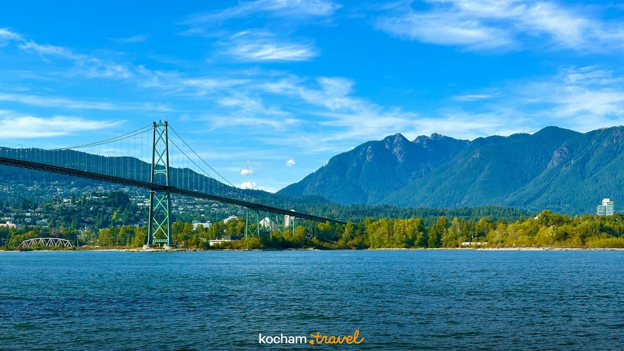 Most Lions Gate, Vancouver, błękitna woda i zalesione góry.