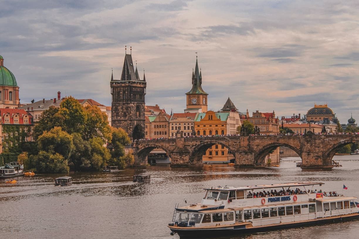 Praga: Most Karola, rzeka Wełtawa, zabytkowe budynki i łodzie wycieczkowe.