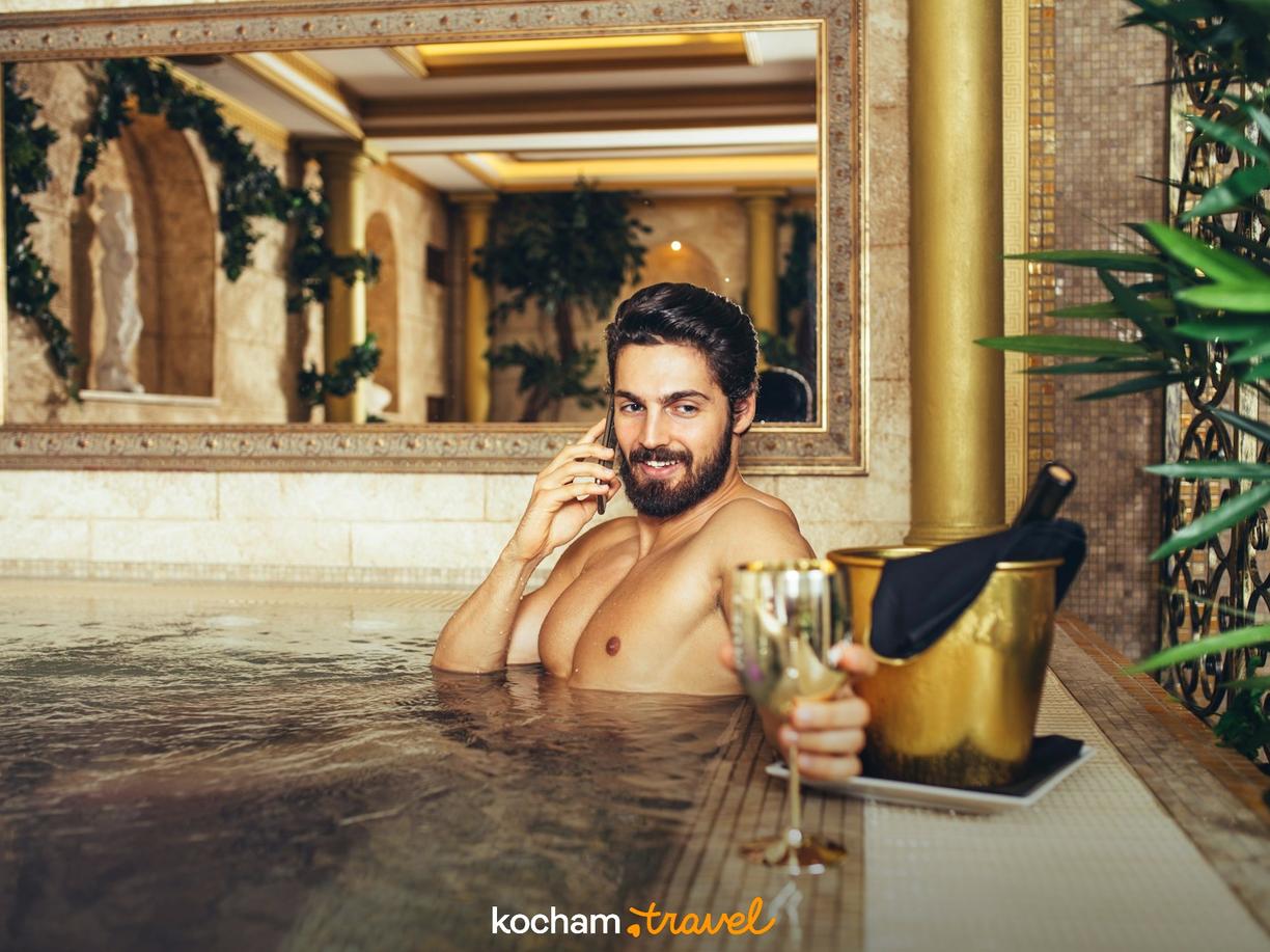 Mężczyzna z brodą relaksujący się w luksusowym jacuzzi z szampanem.
