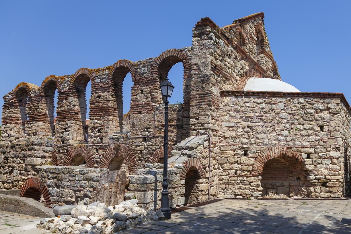 Starożytne ruiny kościoła z kamienia i cegły, liczne łuki architektoniczne.