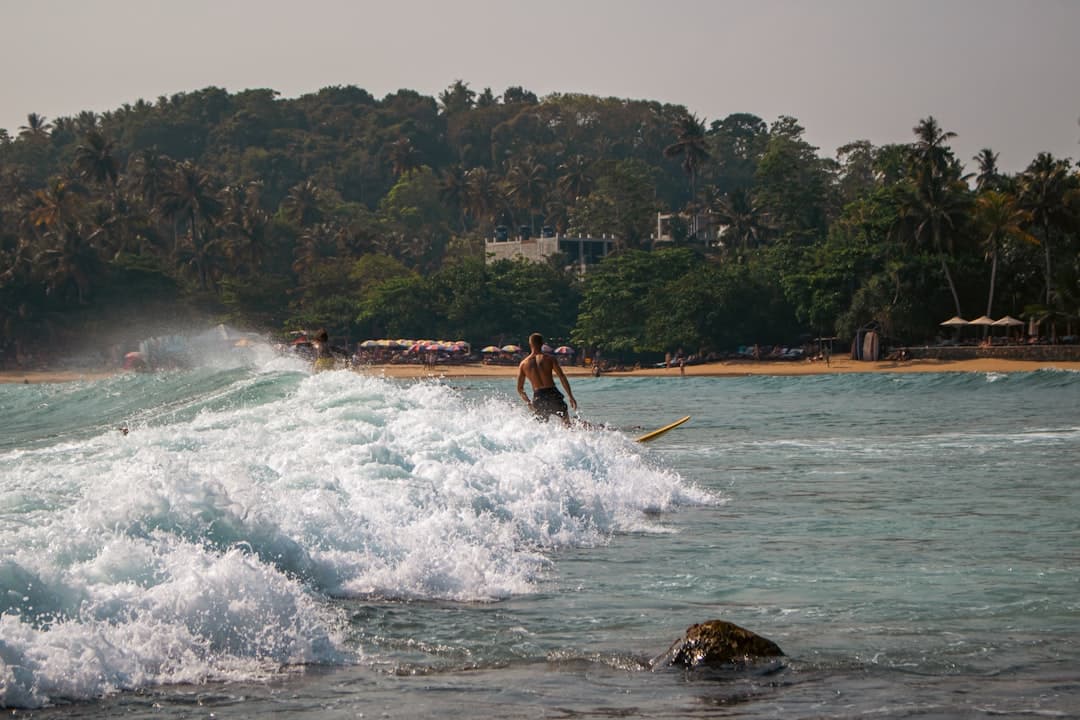 Surfer na fali blisko tropikalnej plaży z palmami
