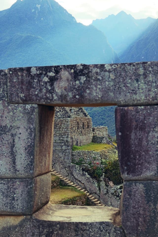 Widok na starożytne Machu Picchu i góry Andów przez kamienne przejście.
