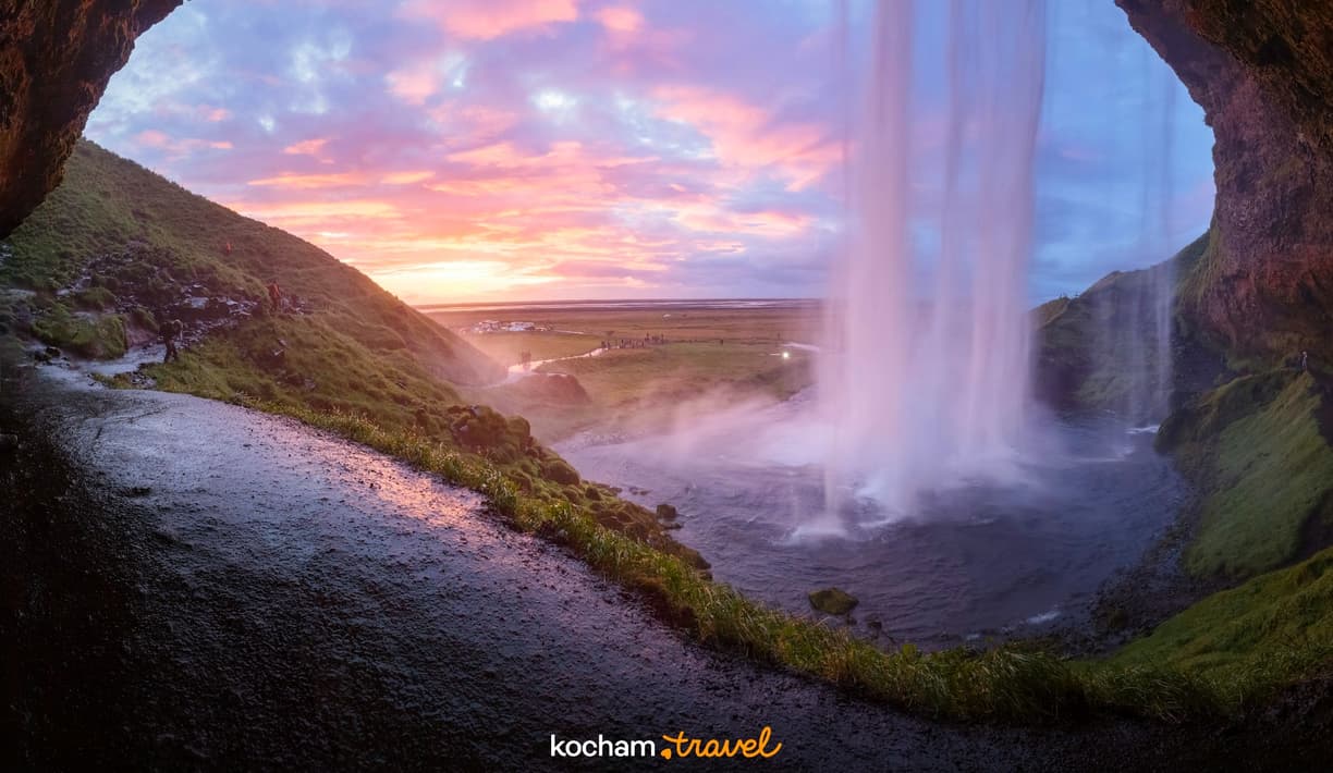 Wodospad Seljalandsfoss w Islandii oglądany zza kaskady przy zachodzie słońca.