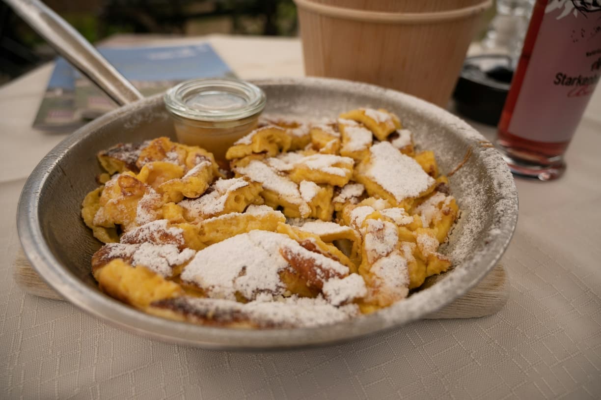 Puszysty Kaiserschmarrn posypany cukrem pudrem z sosem jabłkowym.