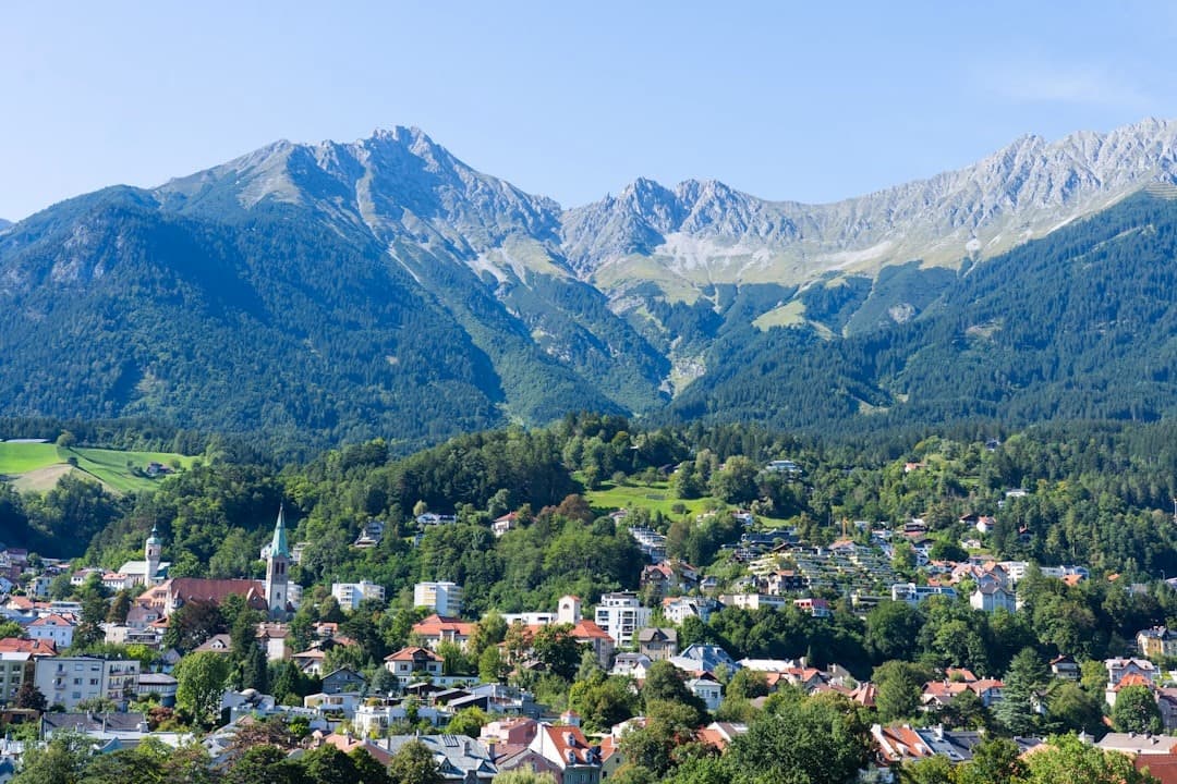 Panoramiczny widok na alpejskie miasto, majestatyczne góry, zielone lasy.