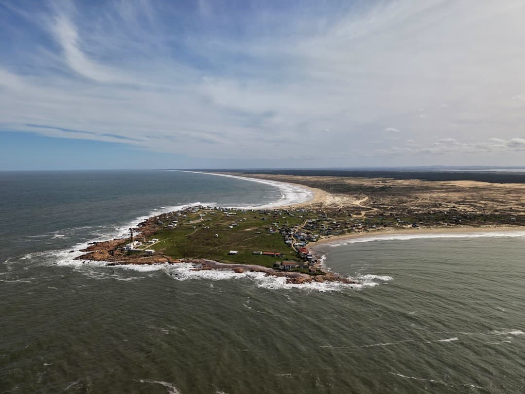 Panoramiczny widok nadmorskiego miasteczka z latarnią morską i plażą.