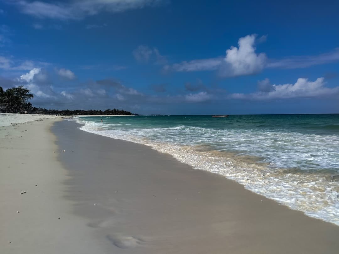Tropikalna plaża z białym piaskiem i turkusową wodą pod błękitnym niebem.