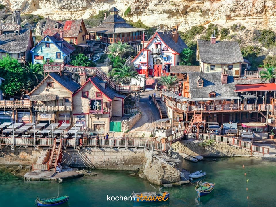 Kolorowa wioska filmowa Popeye'a na Malcie nad turkusową zatoką z łodziami.