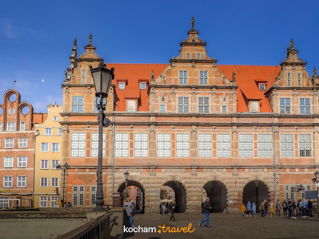 Historyczny budynek Brama Zielona w Gdańsku, ludzie, słoneczny dzień.
