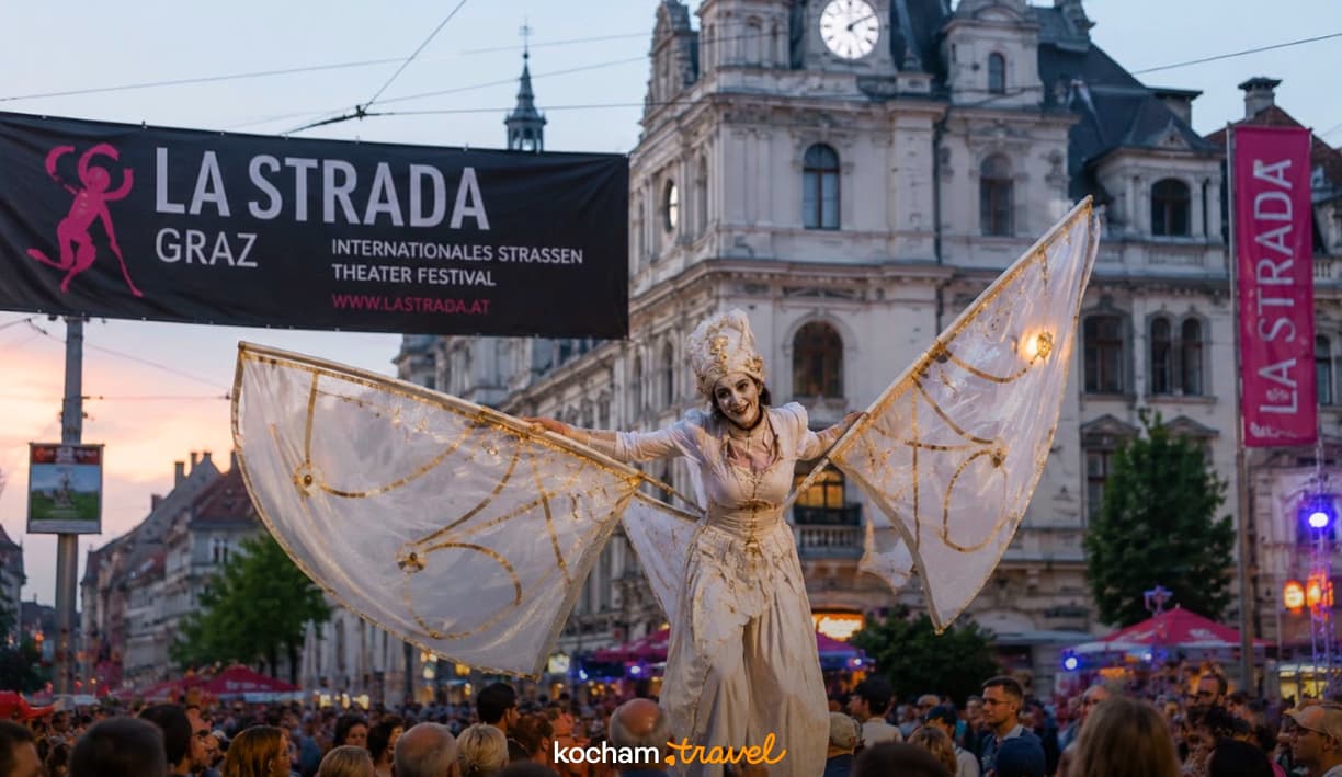 Uliczna artystka na szczudłach w kostiumie ze skrzydłami w Grazu.