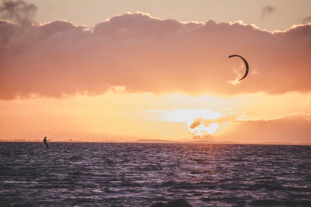 Kitesurfing na morzu, pomarańczowo-różowy zachód słońca.