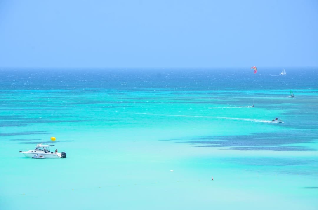 Krystalicznie czyste turkusowe morze, łodzie, kitesurfing i żaglówka.