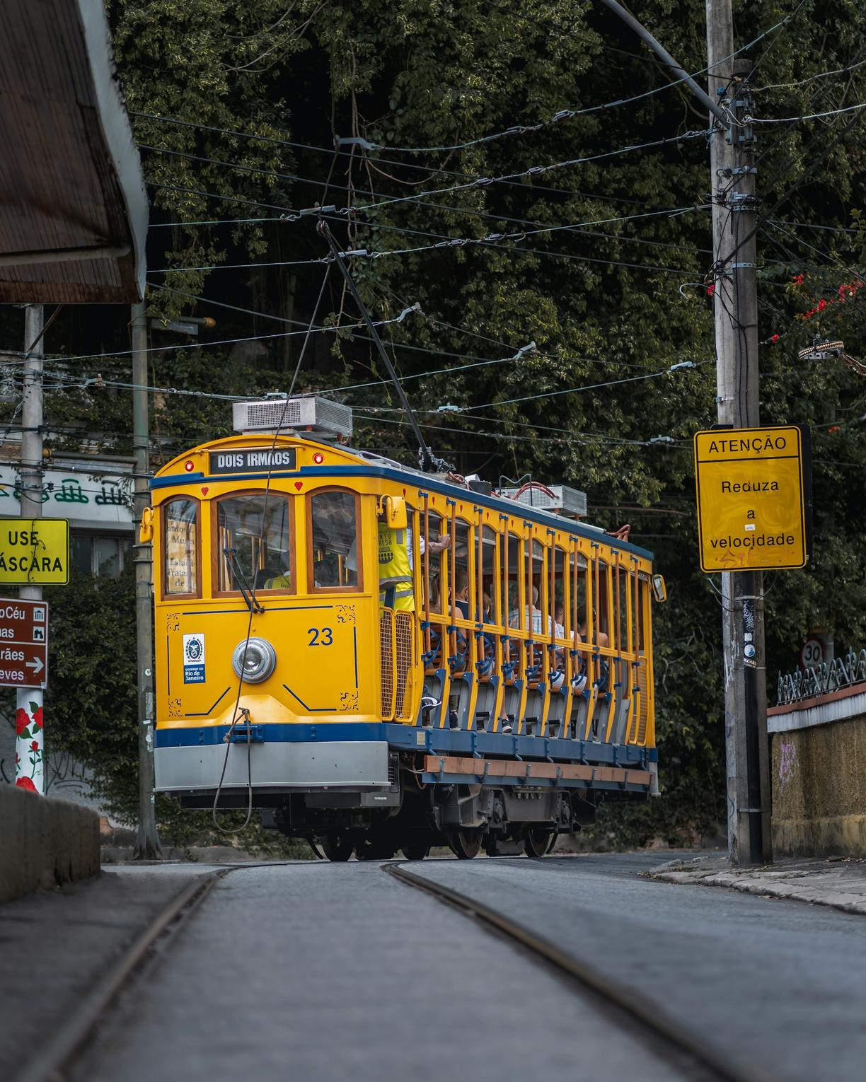 Zabytkowy żółty tramwaj Santa Teresa z pasażerami w Rio de Janeiro.